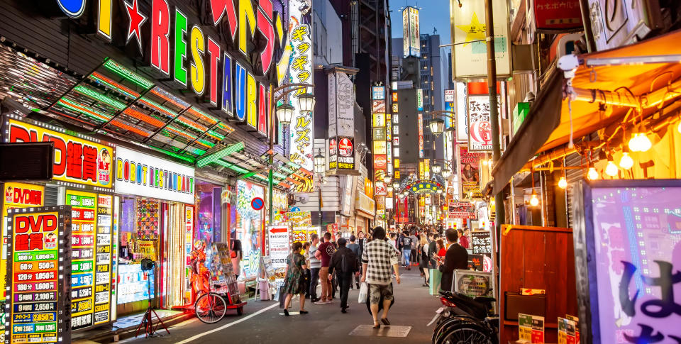 Tokyo, Japan  - June 6; 2022: Scenic view of night neon street in Shinjuku district , people walking on the city street