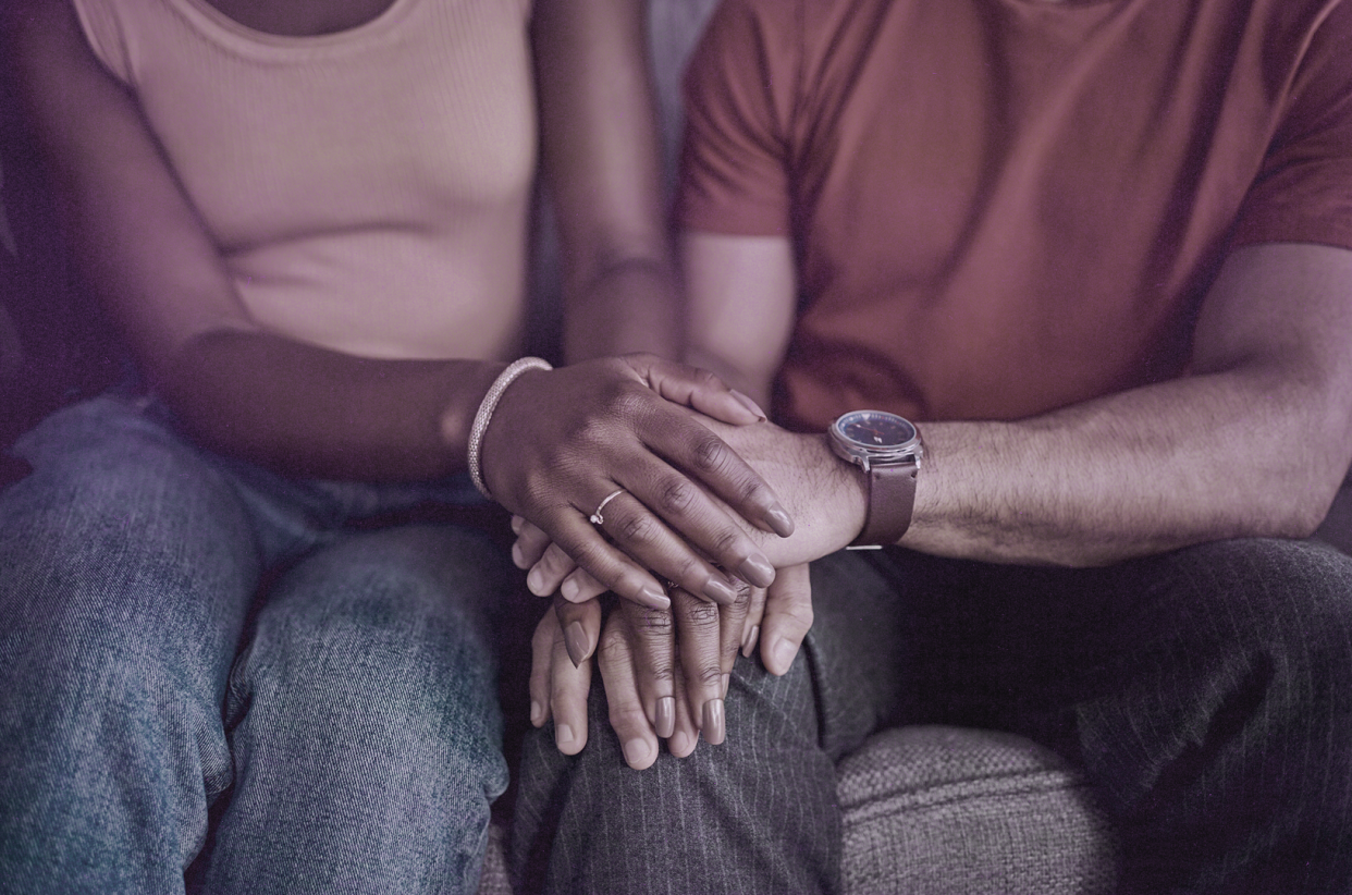 two people sitting side by side with their hands overlapping