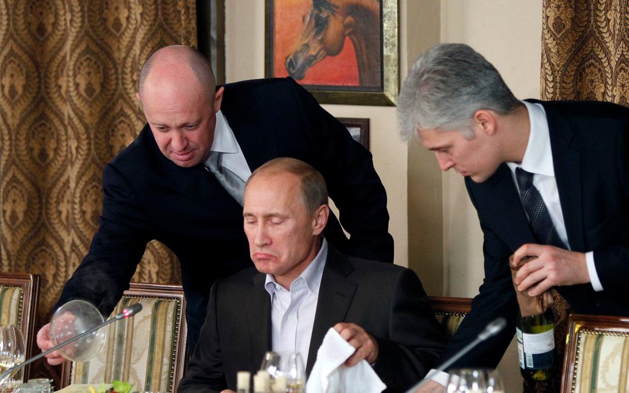 Yevgeny Prigozhin, left, serves food to the then Russian Prime Minister Vladimir Putin in 2011 - AP POOL