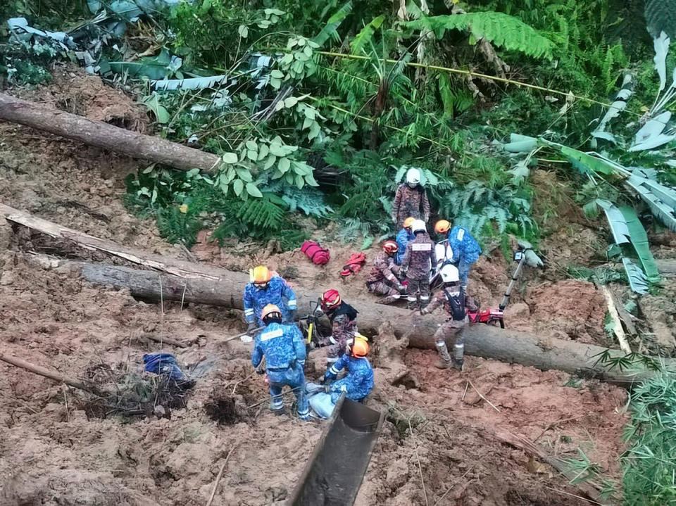 Civil Defense personnel search for missing persons after a landslide hit a campsite in Batang Kali, Malaysia (Malaysia Civil Defense via AP)