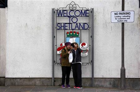 Two women take a selfie photograph in front of a sign in the town of Lerwick on the Shetland Islands April 3, 2014. REUTERS/Cathal McNaughton