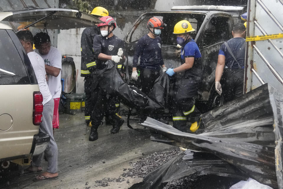 Firemen carry body bag of a victim of a fire in Quezon city, Philippines on Thursday, Aug. 31, 2023. A fire killed more than a dozen people Thursday in a small apparel factory in a Philippine residential area, where firefighters were delayed by flooding, traffic and a wrong address, a fire protection official. (AP Photo/Aaron Favila)