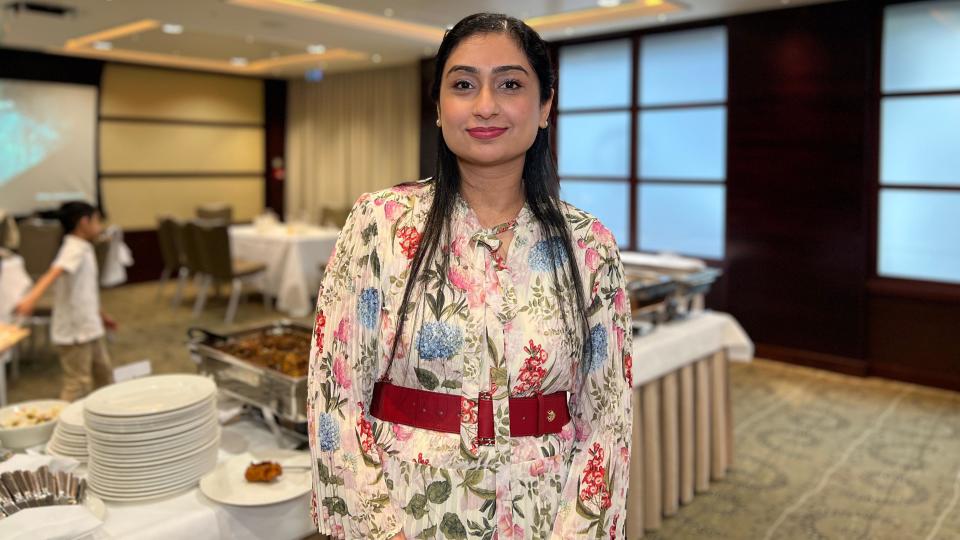 Samya Javid looks at the camera in floral dress in a tradition style standing in front of the food