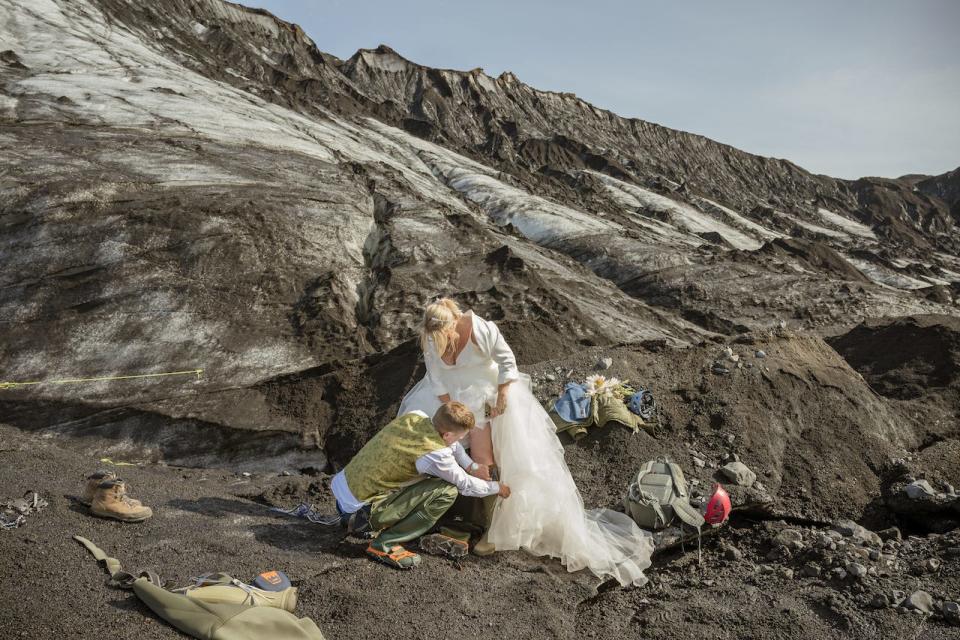 A bride and groom put on boots in Iceland.