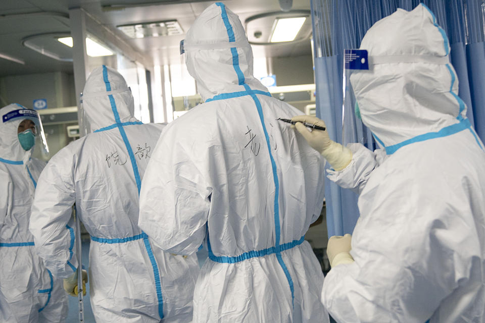 A medical worker writes their colleague's name on a protective suit to aid in identification as they work at Zhongnan Hospital of Wuhan University. Source: AP