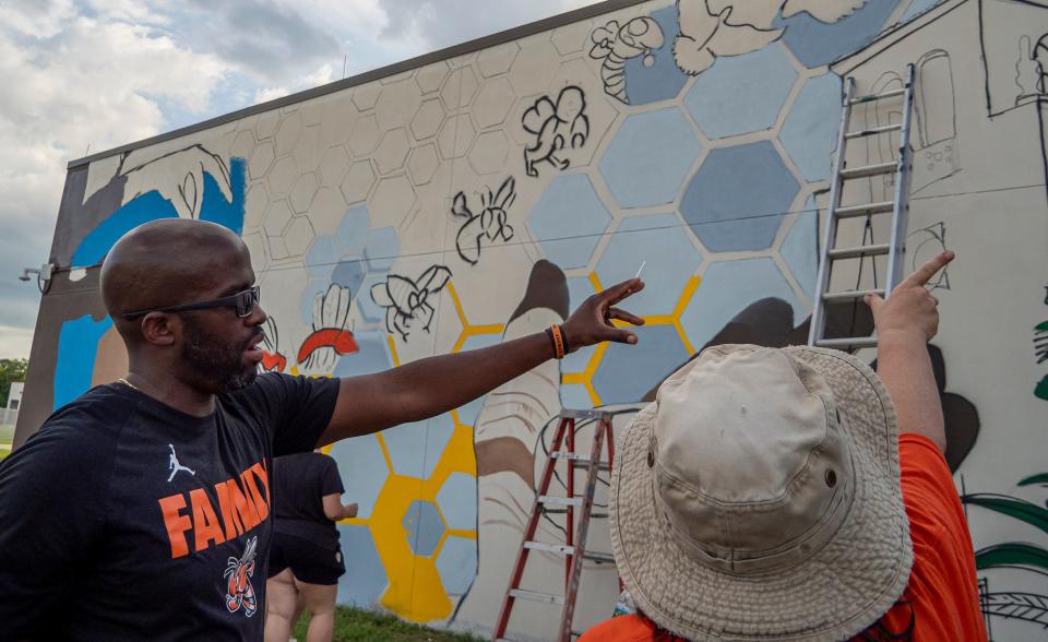 Principal Michael Randolph, left, looks on as people take part in the first day of painting for a mural project at Leesburg High School in Leesburg on Tuesday, May 24, 2022. [PAUL RYAN / CORRESPONDENT]