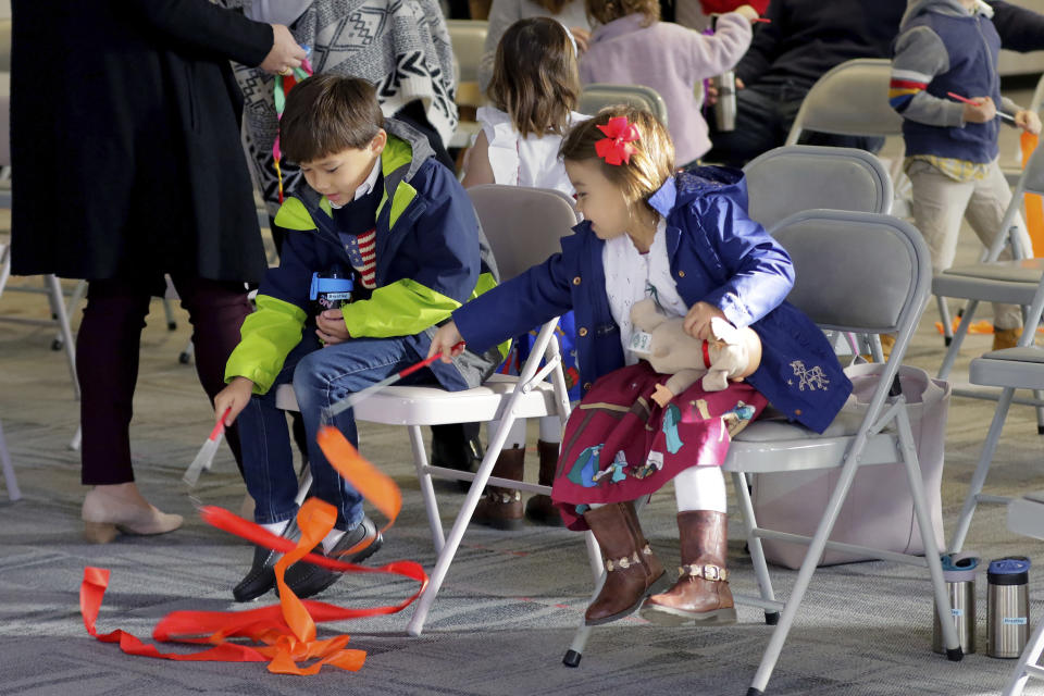 Kids play with streamers during the first service, held in the Fellowship Hall at the Westminster United Methodist Church Sunday, Dec. 12, 2021, in Houston. The church holds two Sunday services. The first is a looser, more contemporary service with an electric band that is better attended by families with children. The second is the traditional service held in the sanctuary. (AP Photo/Michael Wyke)