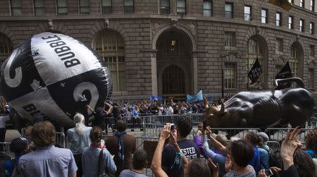The Charging Bull (R) sculpture is seen as police deflate a prop used by protesters during the 'Flood Wall Street' demonstration in Lower Manhattan, New York September 22, 2014. REUTERS/Adrees Latif