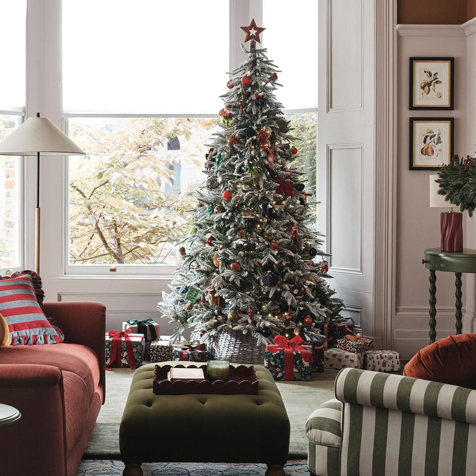  A snow-effect Christmas tree in a living room with decorations from the John Lewis Dawn & Dusk range. 