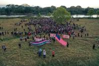 Aerial view of Central American migrants - mostly Hondurans heading in a caravan to the US - holding banners and a US flag after crossing the Suchiate River into Mexico from Guatemala