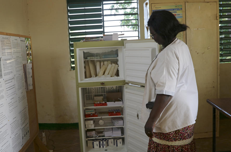 Marguerite Ouangraoua, a nurse at the health clinic in Zeguedessin village on the outskirts of Burkina Faso's capital, Ouagadougou, opens the fridge where the clinic keeps the vaccines, Thursday Oct. 8, 2020. The vaccine cold chain hurdle is just the latest disparity of the pandemic weighted against the poor, who more often live and work in crowded conditions that allow the virus to spread, have little access to medical oxygen vital to COVID-19 treatment, and whose health systems lack labs, supplies or technicians to carry out large-scale testing. (AP Photo/Sam Mednick)