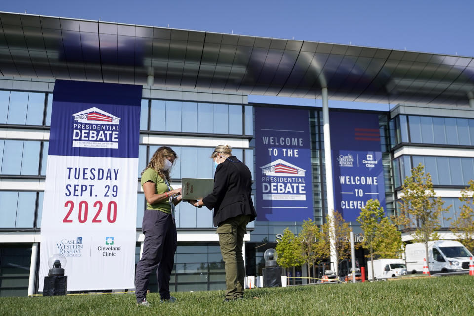 FILE - In this Sunday, Sept. 27, 2020, file photo, women go over a playbook while setting up outside of the Health Education Campus of Case Western Reserve University in Cleveland, ahead of the first presidential debate between Republican President Donald Trump and Democratic candidate and former Vice President Joe Biden. Some of the country’s major sports betting companies are running contests in which participants predict things that will happen or be said during the presidential debate, Tuesday, Sept. 29, 2020, for the chance to win money. (AP Photo/Julio Cortez, File)