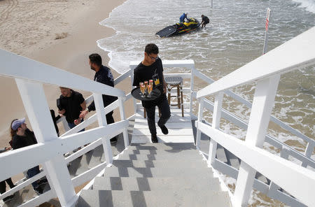 A waiter carries drinks up the stairs of a lifeguard tower to welcome the winners of an international online competition who will spend a night at the tower which was renovated into a luxury hotel suite, at Frishman Beach in Tel Aviv, Israel March 14, 2017. REUTERS/Baz Ratner