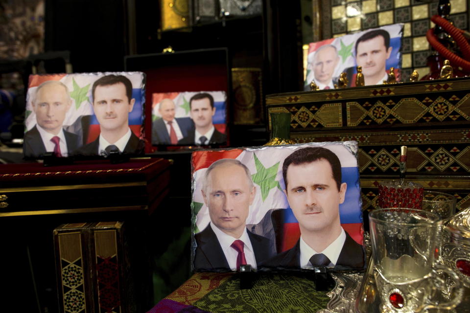 FILE - Photos on porcelain decorated with the images of Russian President Vladimir Putin and Syrian President Bashar Assad are displayed in a souvenir shop in Damascus, Syria, April 18, 2016. Political observers say Russia’s brazen Syria intervention emboldened Putin, giving him a renewed Middle East foothold and helped pave the way for his current attack on Ukraine. (AP Photo/Hassan Ammar, File)