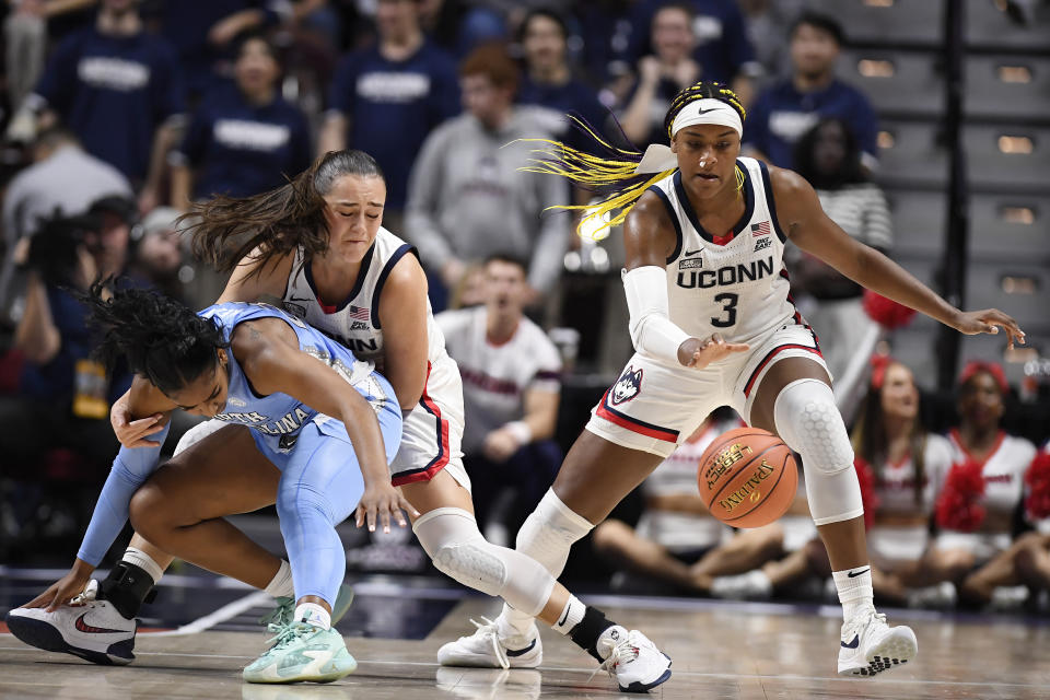 North Carolina guard Deja Kelly, left, looses the ball under pressure from UConn guard Nika Muhl and UConn forward Aaliyah Edwards, right, in the first half of an NCAA college basketball game, Sunday, Dec. 10, 2023, in Uncasville, Conn. (AP Photo/Jessica Hill)