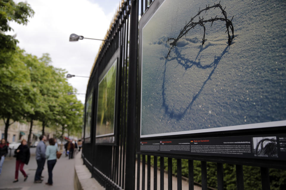 Visitors walk next to " Remains of Barbed Wire" a picture by British photographer Michael St Maur Sheil at the Paris Luxembourg gardens, Tuesday, April 8, 2014 as part of an exhibition " Fields of Battle - Lands of Peace 14-18 ". Captured over a period of seven years, Michael’s photography combines a passion for history and landscape and presents a unique reflection on the transformation of the battlefields of the Great War into the landscape of modern Europe. (AP Photo/Christophe Ena)