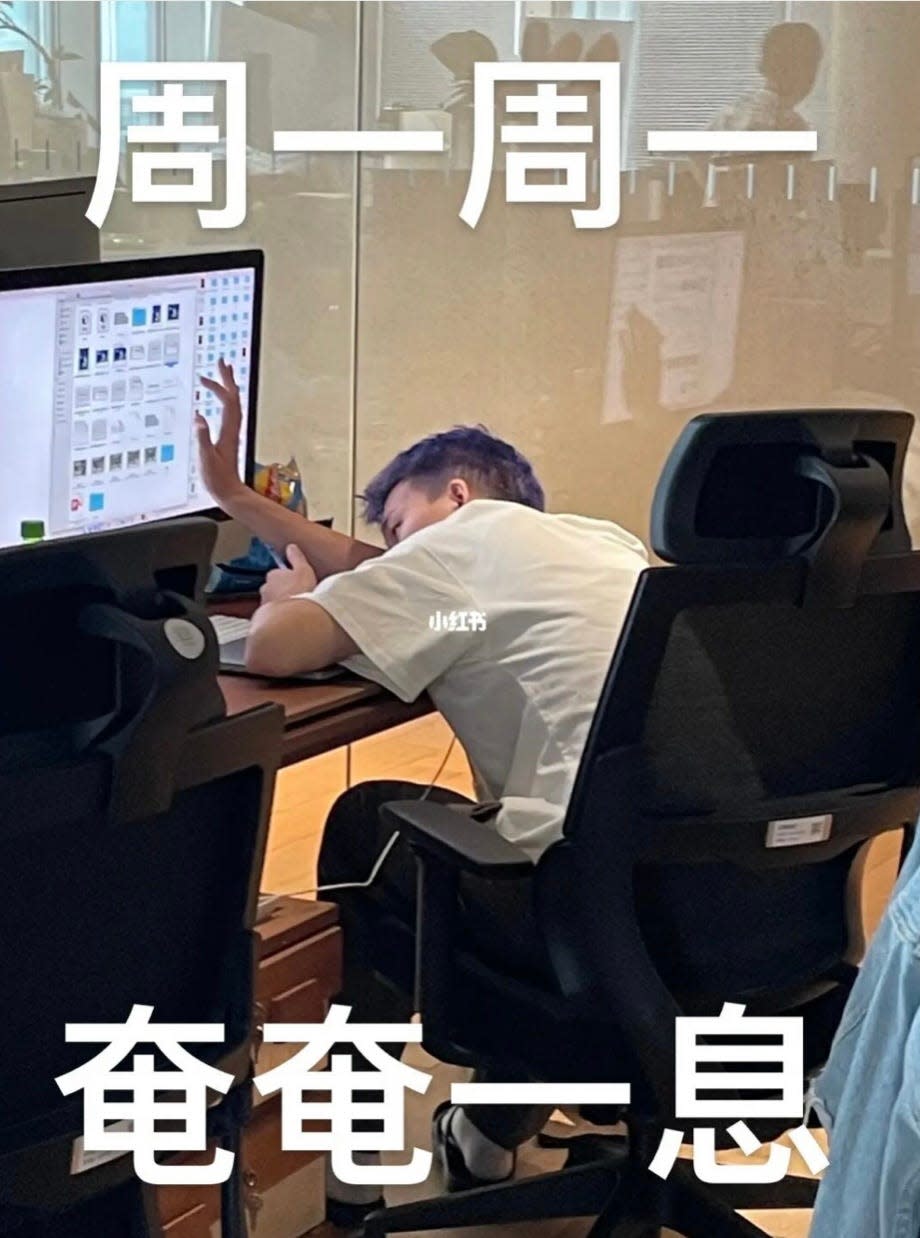 A photo of a person with their head so low it's almost on their desk who looks tired, touching their desktop screen lightly