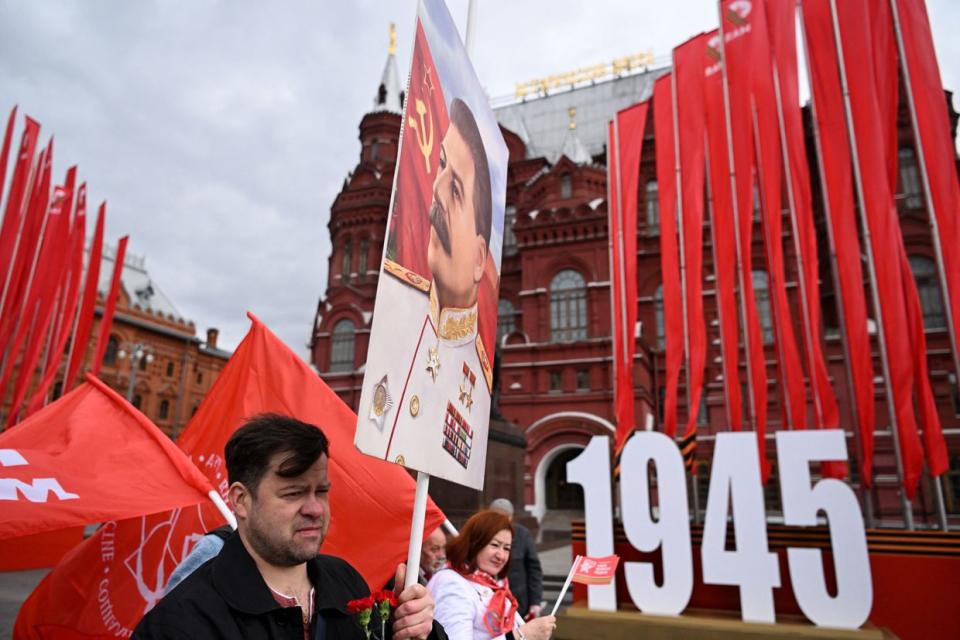 A Russian Communist Party supporter carries a portrait of Soviet tyrant Joseph Stalin in front of the monument of the Marshal of the Soviet Union Georgy Zhukov in Moscow on May 8, 2023, on the eve of the 78th anniversary of the end of the World War II. (Photo by KIRILL KUDRYAVTSEV/AFP via Getty Images)