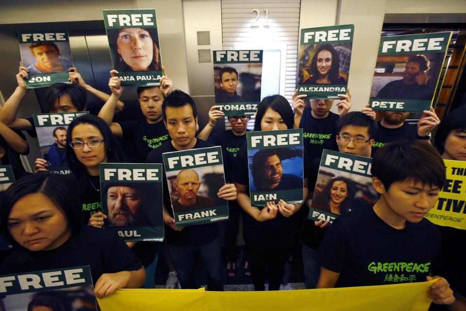 Greenpeace activists in Hong Kong carry portraits of their detained colleagues as they protest outside the Russian Consulate in Hong Kong