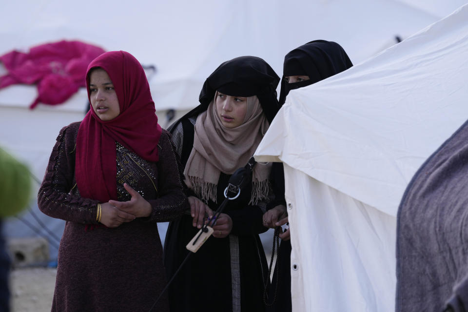 Girls who lost their homes in the devastating earthquake stand outside a tent looking for aid distribution at a shelter camp in Killi, Syria, Sunday, Feb. 12, 2023. The massive earthquake that hit last week is the latest in a litany of hardships for Syrian women, many of whom have been left dependent on aid and alone responsible for their families' well-being. (AP Photo/Hussein Malla)