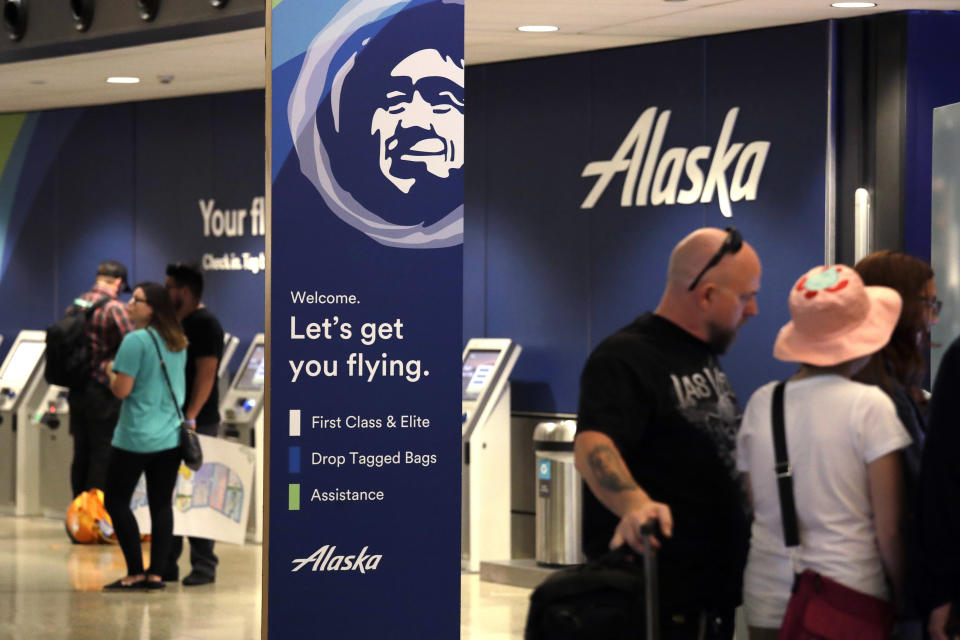 People stand in the Alaska Airlines ticket area at Sea-Tac International Airport Friday, Aug. 10, 2018, in SeaTac, Wash.An airline mechanic stole an Alaska Airlines plane without any passengers and took off from Sea-Tac International Airport in Washington state on Friday night before crashing near Ketron Island, officials said. (AP Photo/Elaine Thompson)