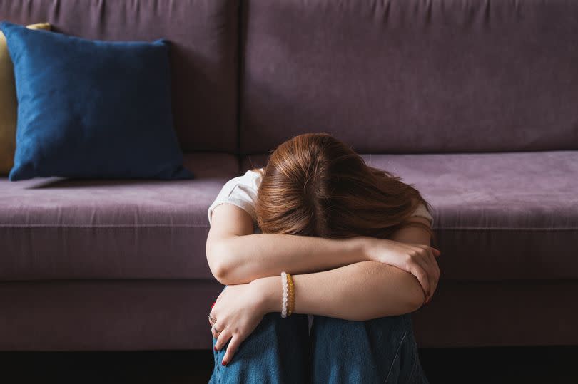 Upset depressed teenager covering face with hands and crying