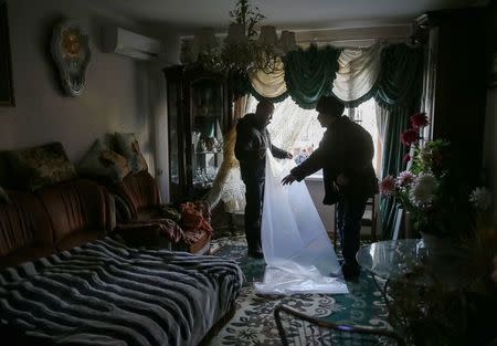Local residents prepare plastic sheeting to cover broken windows in their flat at a residential sector affected by shelling in Kramatorsk, eastern Ukraine February 11, 2015. REUTERS/Gleb Garanich