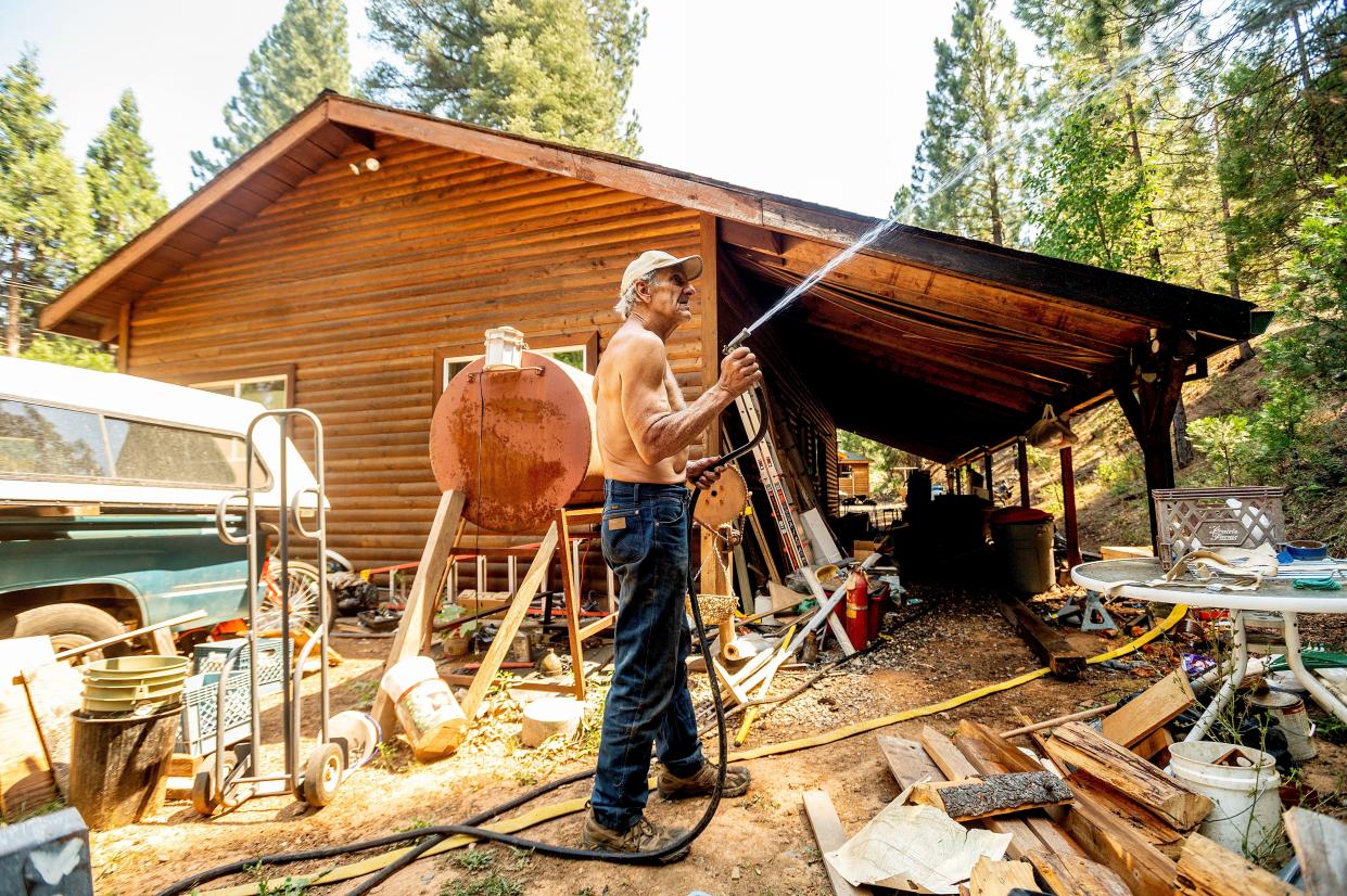 Dan Santos sprays water while defending his girlfriend's Greenville home as the Dixie Fire burns nearby in Plumas County, Calif. on Tuesday, Aug. 3, 2021. Dry and windy conditions have led to increased fire activity as firefighters battle the blaze which ignited July 14.