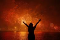A woman celebrates the New Year as she watches fireworks exploding above Copacabana beach in Rio de Janeiro January 1, 2013. More than two million people gathered along Rio's most famous beach to witness the 20-minute display and celebrate the beginning of a new year.
