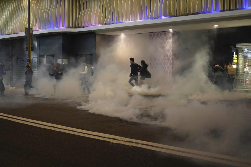 Residents react to tear gas as police and protesters confront each other on Christmas Eve in Hong Kong on Tuesday, Dec. 24, 2019. More than six months of protests have beset the city with frequent confrontations between protesters and police. (AP Photo/Kin Cheung)