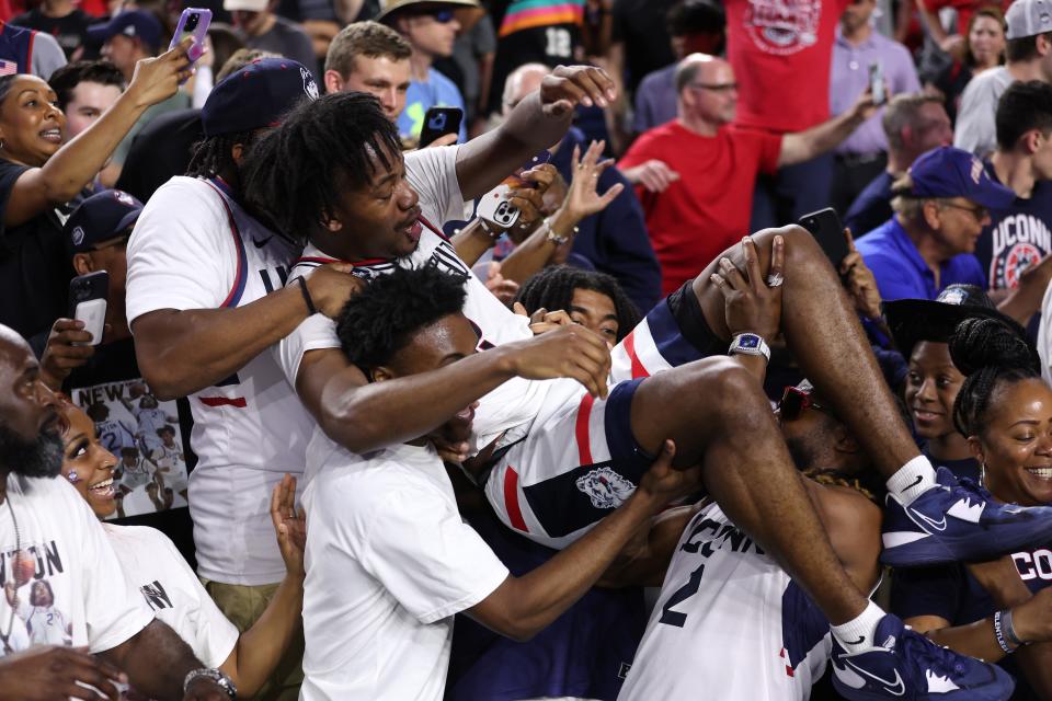 Packers running back Aaron Jones, right, carries his cousin, UConn senior Tristen Newton, after the Huskies defeated the San Diego State Aztecs, 76-59, during the NCAA men's basketball national championship game Monday, April 3, 2023, at NRG Stadium in Houston.
