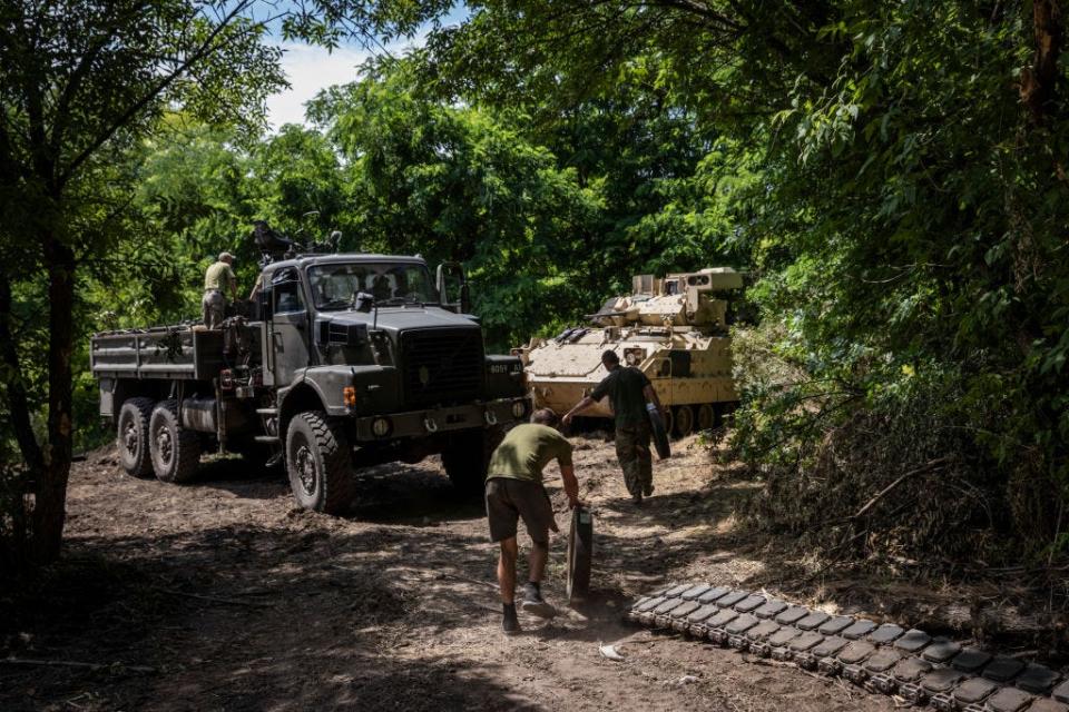 Soldiers and mechanics from Ukraine's 47th Mechanized Brigade go to change the wheels and tracks of a damaged US made Bradley Fighting Vehicle at a secret workshop in a wooded area in Zaporizhzhia Region, Ukraine