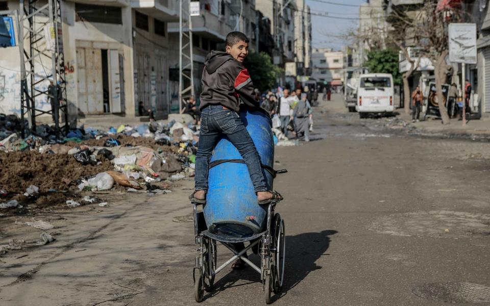 Palestinian people collect usable items among piles of rubble and ash