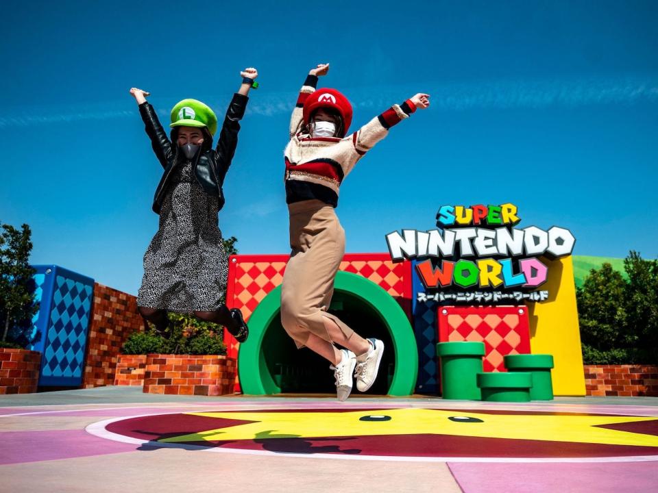 In this picture taken on March 17, 2021, fans of Universal Studio Japan pose at the entrance of the Super Nintendo World, during a media preview of the theme park in Osaka.