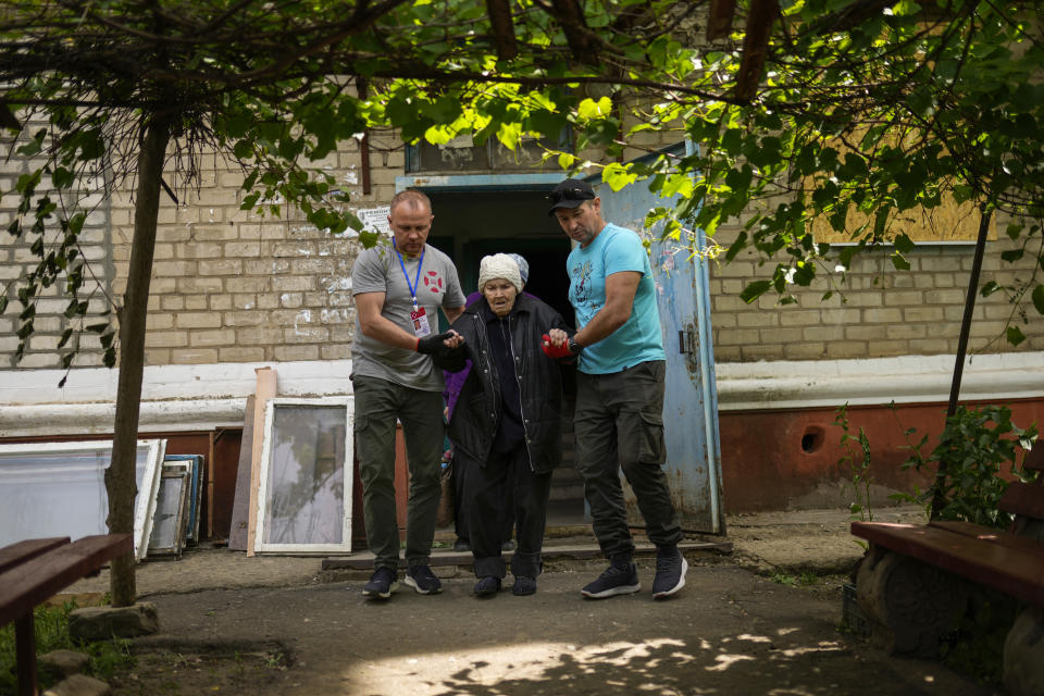 A woman is evacuated by volunteers of Vostok SOS charitable organisation in Kramatorsk, eastern Ukraine, Thursday, May 26, 2022. Residents in villages and towns near the front line continue to flee as fighting rages in eastern Ukraine. (AP Photo/Francisco Seco)