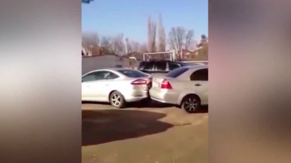 Bewildered by-standers watch on as the woman repeatedly crashes into parked cars. Photo: YouTube