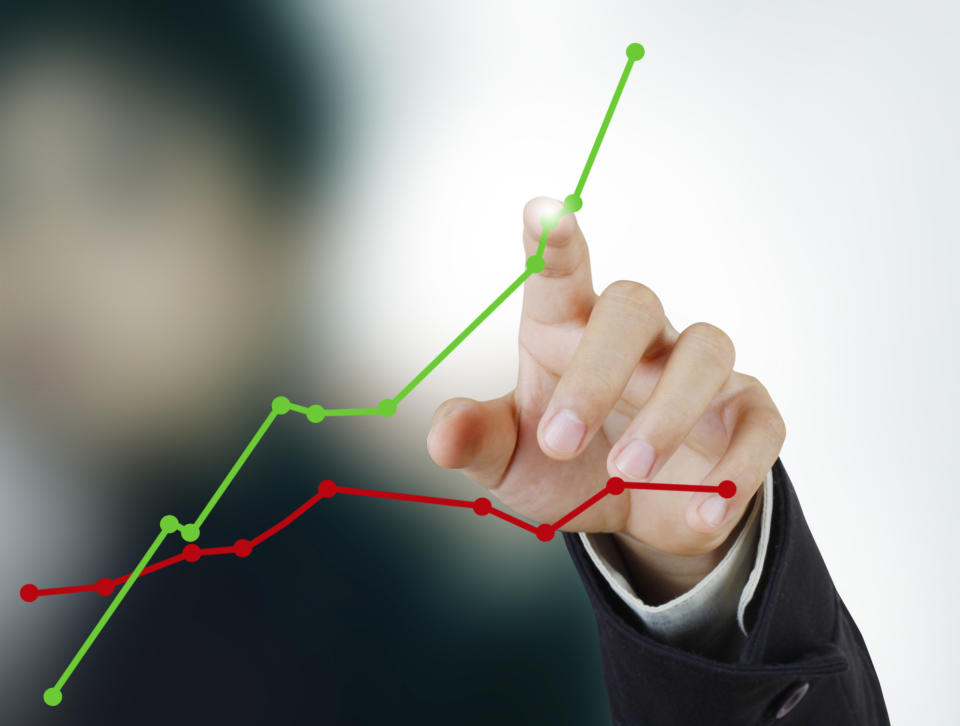 A person pointing to an upwardly sloping line chart that's above a flat line chart