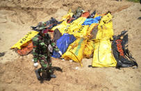 An Indonesian soldier walks past the bodies of tsunami and earthquake victims for a mass burial in Palu, Central Sulawesi, Indonesia, Tuesday, Oct. 2. 2018. Desperation was visible everywhere Tuesday among victims receiving little aid in areas heavily damaged by a massive earthquake and tsunami, four days after the disaster devastated parts of Indonesia's central Sulawesi island. (AP Photo/Rifki)