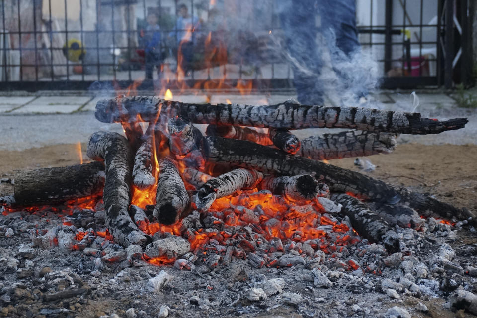 Boys play soccer in a house garden next to a fire that, once reduced to smoldering coals, would be crossed by devotees carrying icons of St. Constantine in a ritual in the Orthodox saint's honor in Lagkadas, Greece, on Monday, May 22, 2023. Groups of devotees of St. Constantine called "anastenaria" celebrate his feast day with elaborate rituals that were once prohibited by the church but participants regard as intimately connected to their Christian faith. (AP Photo/Giovanna Dell'Orto)