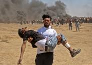 <p>A Palestinian carries an injured protester during clashes with Israeli forces near the border between the Gaza Strip and Israel on May 14, 2018, during a demonstration on the day of the U.S. Embassy move to Jerusalem. (Photo: Mahmud Hams/AFP/Getty Images) </p>