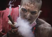 A Naga Sadhu or Naked Hindu holy man smokes before taking a holy dips in the river Ganges during Shahi snan or a Royal bath during Kumbh mela, in Haridwar in the Indian state of Uttarakhand, Monday, April 12, 2021. As states across India are declaring some version of a lockdown to battle rising Covid cases as part of a nationwide second-wave, thousands of pilgrims are gathering on the banks of the river Ganga for the Hindu festival Kumbh Mela. The faithful believe that a dip in the waters of the Ganga will absolve them of their sins and deliver them from the cycle of birth and death. (AP Photo/Karma Sonam)