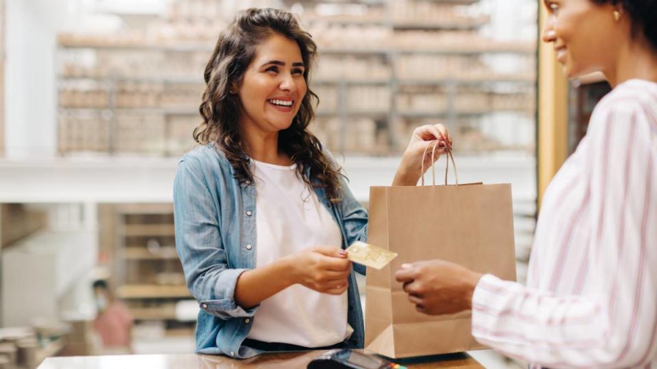 Last minute Christmas gifts: Happy female customer paying with a credit card in a ceramic store