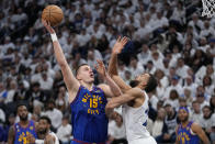 Denver Nuggets center Nikola Jokic (15) shoots against Minnesota Timberwolves center Rudy Gobert during the second half of Game 3 of an NBA basketball first-round playoff series Friday, April 21, 2023, in Minneapolis. (AP Photo/Abbie Parr)