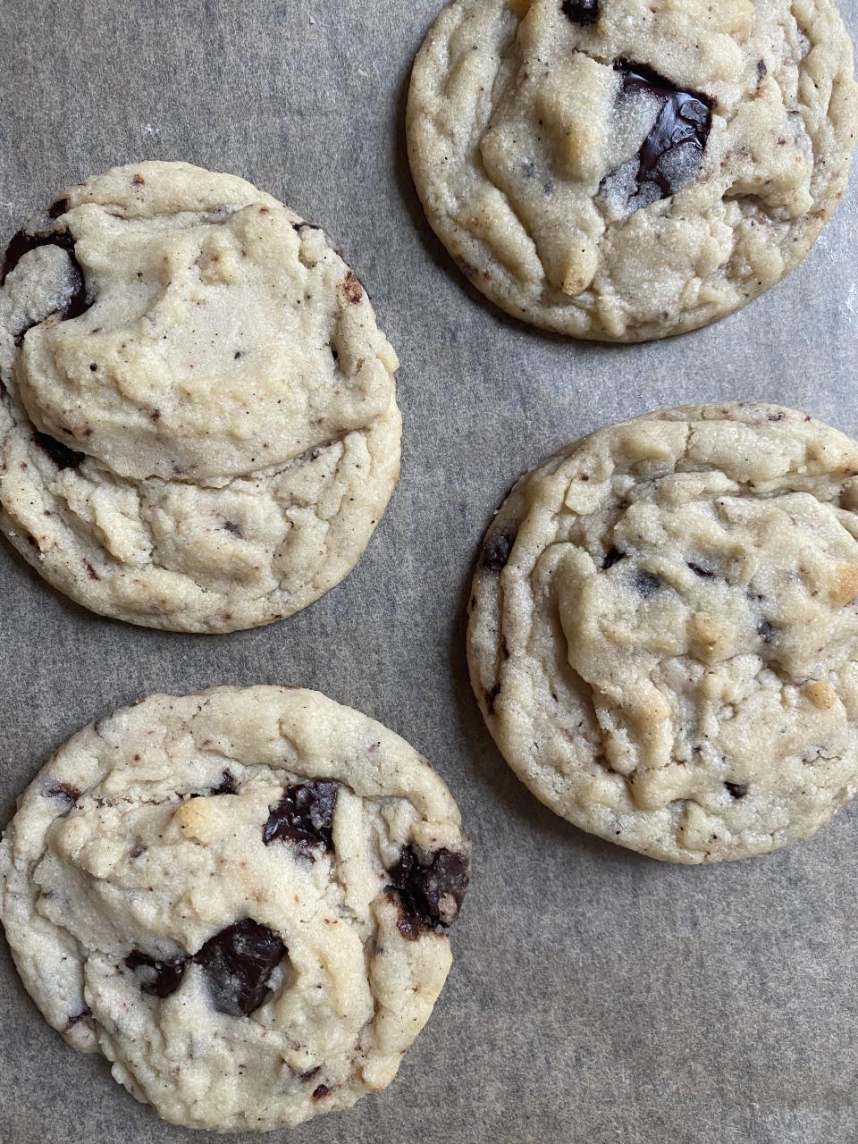 Four freshly baked tiramisu cookies with visible chocolate chunks on a tray