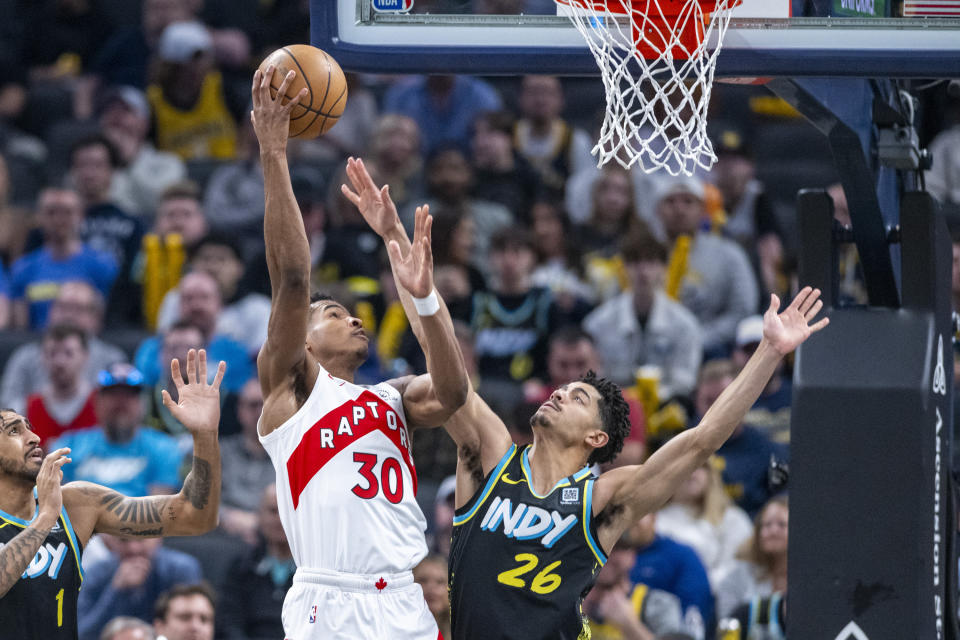 Toronto Raptors guard Ochai Agbaji (30) shoots while defended by Indiana Pacers guard Ben Sheppard (26) during the first half of an NBA basketball game in Indianapolis, Monday, Feb. 26, 2024. (AP Photo/Doug McSchooler)