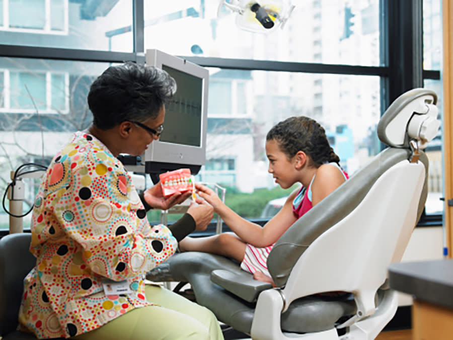 A dental care provider works with a young patient