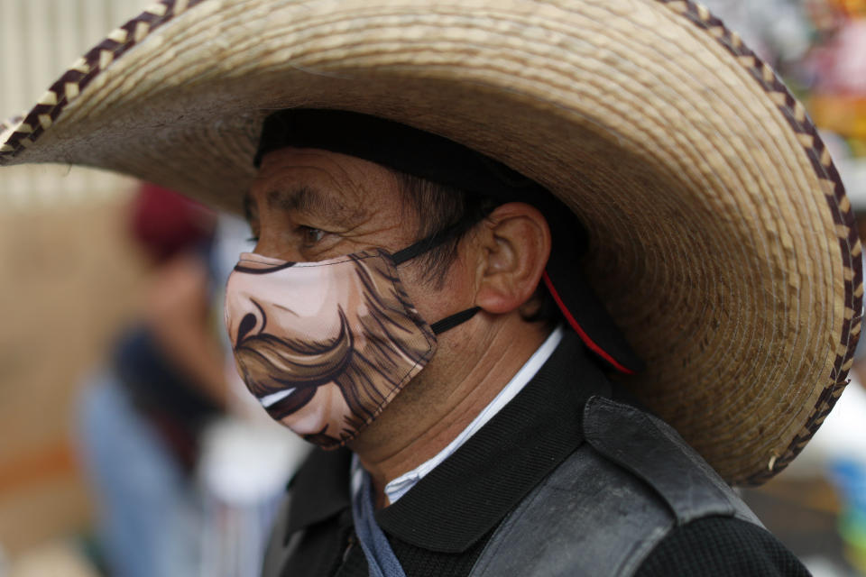 A man wearing a protective face mask walks amidst outdoor stalls at the Mercado Sonora, which reopened ten days ago with measures to reduce congestion and limit the spread of the new coronavirus, in Mexico City, Thursday, June 25, 2020. With Latin America now the epicenter of the pandemic, but with hundreds of millions relying on these markets for food and livelihoods, the debate now centers on whether and how they can ever operate safely. (AP Photo/Rebecca Blackwell)