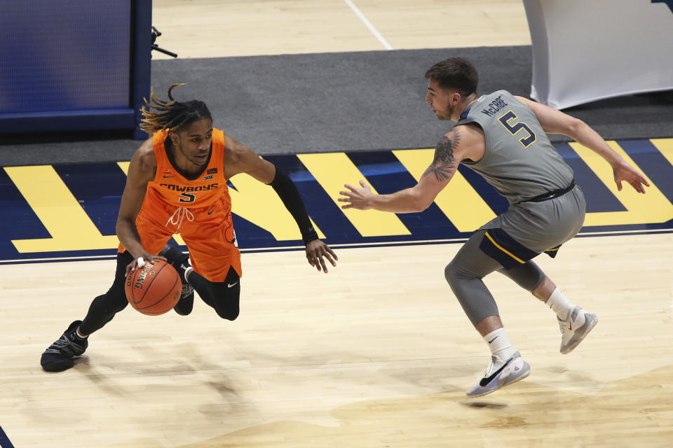 Oklahoma State guard Rondel Walker (5) is defended by West Virginia guard Jordan McCabe (5) during the first half of an NCAA college basketball game Saturday, March 6, 2021, in Morgantown, W.Va. (AP Photo/Kathleen Batten)
