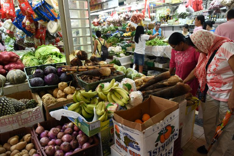 People shop for vegetables at a wet market in the Little India district of Singapore on August 14, 2014