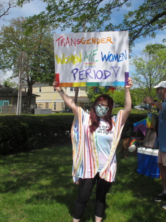 Charlie Milana of Philadelphia holds a sign during a protest in Neptune N.J., Friday, May 7, 2021, against a school vice principal who was filmed tossing beer at people who were videotaping his wife's rant against a transgender woman's use of a public restroom at an outdoor restaurant in Galloway Township N.J. in April. (AP Photo/Wayne Parry)